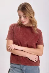 Remera color terracota con cuello redondo y estrellas bordadas alrededor del cuello.