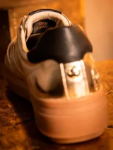 Zapatillas deportivas doradas de cuero con cordones color beige y suela marrón.