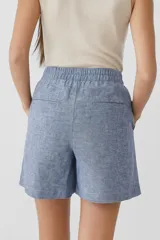 Short de lino de tiro alto, corte ancho y largo hasta la mitad del muslo, con estampado de rayas verticales blancas y azul oscuro.