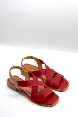 Sandalias bajas color beige con tiras cruzadas y elástico dorado en el talón.