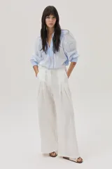 Blusa celeste a rayas verticales blancas, con cuello mao con lazos, mangas abullonadas y corte imperio.