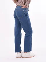 Jean de mezclilla azul de tiro alto, corte acampanado (bootcut) y largo con ruedo deshilachado.