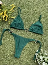 Conjunto de bikini verde con corpiño triangular con argolla metálica en el centro y bombacha colaless con tiras para atar y argollas en los costados.