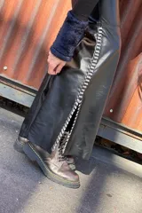 Pantalón Oxford negro de cuero sintético con cierre frontal y aberturas laterales con pasamanería plateada.