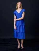 Vestido blanco de gasa con capas de la marca Julia Jordan. Tiene escote en V, mangas cortas con volados, corte en la cintura, abertura central en la espalda con cierre invisible y forro interno a tono.