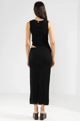 Falda midi negra de punto con abertura lateral y detalle de botón metálico con logo.