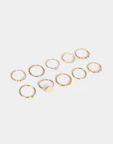 Set de 10 anillos dorados de metal con diferentes diseños, algunos con perlas y otros con strass.