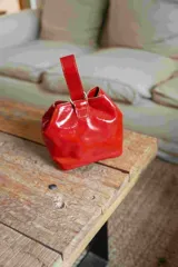 Mini bag tipo limosnera color rojo charol, con asa corta y cierre superior fruncido.