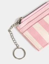 Tarjetero de cuerina color crema con estampado de corazones, flores y textos alusivos a Tokio y Kioto. Tiene cierre superior y mosquetón metálico plateado.