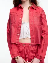 Campera corta de denim color rojo con textura metalizada, cuello camisero, cierre frontal con botones a presión, bolsillos de parche en el pecho y ruedo desflecado.