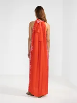 Vestido largo color naranja con estampado de flores rosas, corte recto, cuello halter y espalda descubierta.