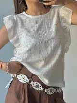 Blusa blanca con textura arrugada, cuello redondo y mangas cortas con volados.