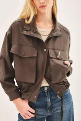 Campera marrón de lino con cierre frontal y bolsillos con solapa. Tiene mangas largas con presilla interna para arremangar.