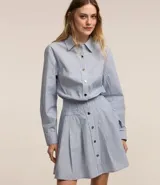 Vestido corto camisero de tricolina de algodón a rayas celestes y blancas, con cuello solapa, abotonado delantero, mangas largas y cintura marcada.