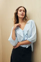 Blusa negra con mangas 3/4 y escote en V con volados.