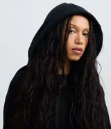 Saco negro de algodón con felpa, con capucha ajustable mediante cordón, mangas largas, cierre delantero de cremallera y bolsillos funcionales.