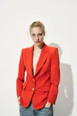 Blazer color rojo con cuello solapa, manga larga con hombreras, bolsillos delanteros con solapa y cierre frontal con botones dorados.