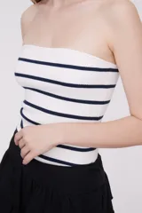 Top sin mangas blanco con rayas horizontales azul marino, ajustado al cuerpo.