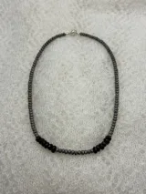 Collar corto de cuentas facetadas de hematita gris con detalles de cuentas de granate rojo oscuro.