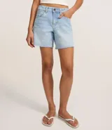 Bermuda de denim para mujer con cintura media y bajo deshilachado. Cuenta con trabillas en la cintura, cierre tradicional y bolsillos funcionales. Confeccionada en algodón con un toque de elastano.