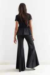 Top negro de manga corta y cuello redondo. La parte superior es de tejido liso y ajustado, mientras que la parte inferior es un bajo globo con textura plisada y semitransparente.