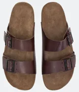 Sandalias tipo slide de cuero color marrón con dos tiras anchas ajustables con hebillas metálicas. Suela plana con textura. Marca Viko.
