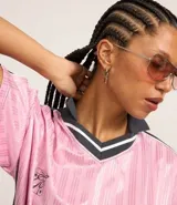 Remera rosa con cuello polo gris y rayas verticales. Estampado frontal con la palabra "gobline" en letras cursivas y la frase "in my best era". Diseño oversized con mangas cortas y recortes laterales en color negro.