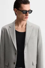 Blazer regular fit color gris claro confeccionado en tejido con lana. Tiene cuello con solapas de muesca, manga larga con puño abotonado, bolsillo de vivo en el pecho, bolsillos de solapa en la cadera, bolsillo interior, aberturas en la espalda y cierre frontal con botones.