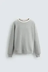 Sudadera gris de tejido compacto con mezcla de algodón y viscosa, corte relaxed fit, cuello redondo con rib combinado a contraste, manga larga y acabados en rib.