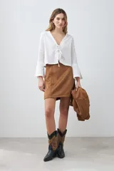 Minifalda color tostado de simil gamuza, corte recto y cierre trasero invisible.