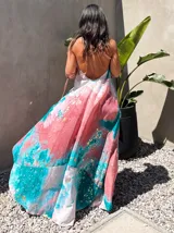 Vestido largo de tela fluida, color verde esmeralda con estampado abstracto en tonos turquesa y detalles dorados. Diseño asimétrico con un solo tirante tejido en el hombro.