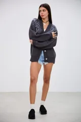 Saco de punto grueso color gris oscuro, con escote en V y cierre frontal de botones. Presenta detalles bordados con lentejuelas y abalorios en los hombros y la parte superior de las mangas.