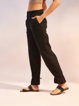 Pantalón negro de lino con corte recto, cintura alta y detalle de lazos en los tobillos.