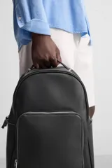 Mochila negra con acabado grabado, compartimento principal con cierre de cremallera, espacio interior para dispositivos electrónicos de hasta 13 pulgadas y bolsillo con cremallera. Bolsillo frontal con cremallera, parte posterior acolchada con banda de sujeción para equipaje, asa de mano y dos asas de hombro ajustables y acolchadas.
