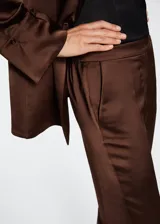 Pantalón recto de tejido satinado color marrón, con cintura elástica y diseño fluido.