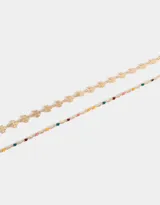Set de dos pulseras doradas con dijes: una con dijes de trébol y otra con dijes esmaltados de colores.