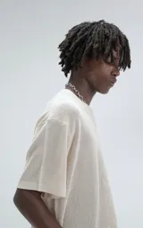 Remera de tejido de punto color beige con moldería ligeramente oversize, cuello redondo y mangas cortas. Confeccionada en una mezcla de viscosa y poliéster que ofrece una caída fluida y textura suave.