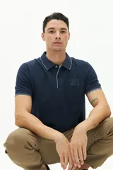 Polo color beige con textura, corte regular, logo estampado en el pecho y mangas cortas con ribete blanco.