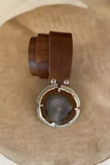 Cinto de cuero azul con hebilla circular de piedra ágata con borde dorado.
