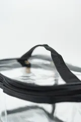 Neceser transparente con cierre superior y ribetes negros.