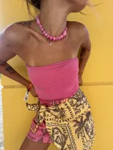 Falda corta tipo pareo de color amarillo con estampado de palmeras y motivos gráficos en contraste. Presenta un diseño ajustable mediante un lazo lateral y está confeccionada en una mezcla de viscosa y lino.