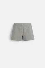 Short de baño con textura seersucker a rayas verticales azul marino y blanco. Tiene cintura elástica ajustable con cordón, bolsillos frontales y traseros, aberturas laterales en el bajo y forro interior.