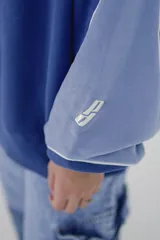 Buzo azul con mangas raglán en tono celeste y puños ajustados. Estampa frontal con la palabra "CONFIDENTIAL" en mayúsculas.