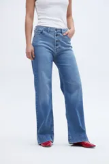 Pantalón jean celeste de corte holgado con pierna ancha y tiro alto. Tiene bolsillos delanteros y traseros, y cierre frontal con botones a la vista.