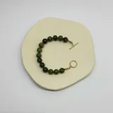 Pulsera elástica con cuentas de jade verde de 10mm y separadores de hilo verde. Cierre tipo toggle enchapado en oro.