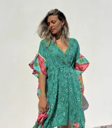 Túnica corta verde con estampado de flores rojas y detalles bordados. Mangas anchas con terminación en volados con estampado floral en tonos rosa y celeste.