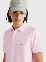 Chomba rosada de Tommy Hilfiger, modelo 1985, de corte regular, con cuello tipo chomba, cartera de dos botones, mangas cortas y logo bordado en el pecho. El interior del cuello es rayado.