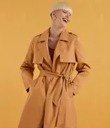 Campera trench coat larga color camel, con cuello con solapa, manga larga, abertura frontal con doble botonadura, dos bolsillos laterales, trabillas en la cintura y cinturón para amarrar.