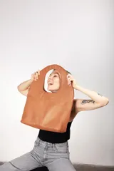 Bolso tote de cuero color marrón claro, con manijas circulares y logo grabado en el frente.