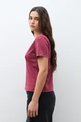 Remera de algodón color bordó, con cuello redondo, manga corta y detalle de ojalillos metálicos en el borde de las mangas.